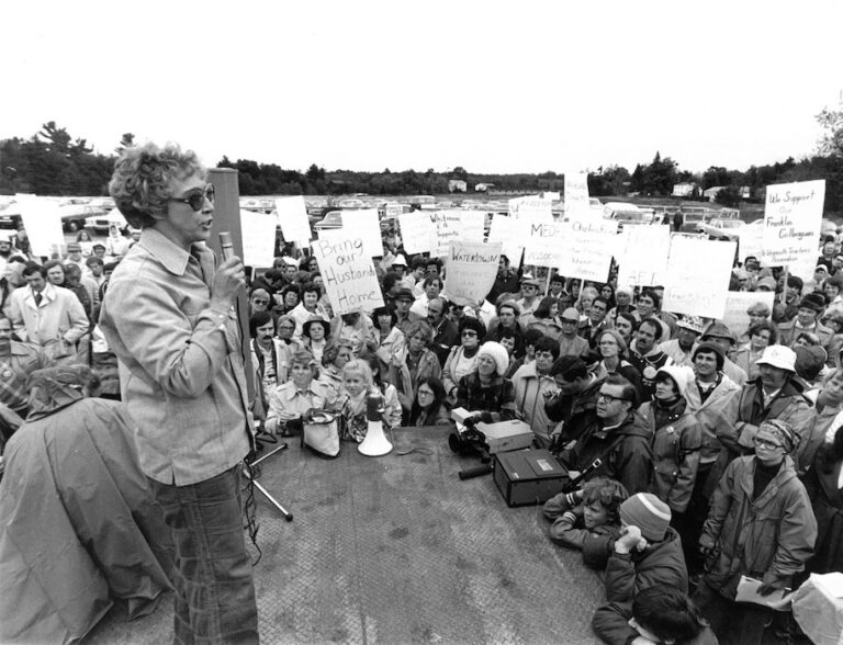 Woman speaking in front of a crowd holding signs supporting the Franklin strike.