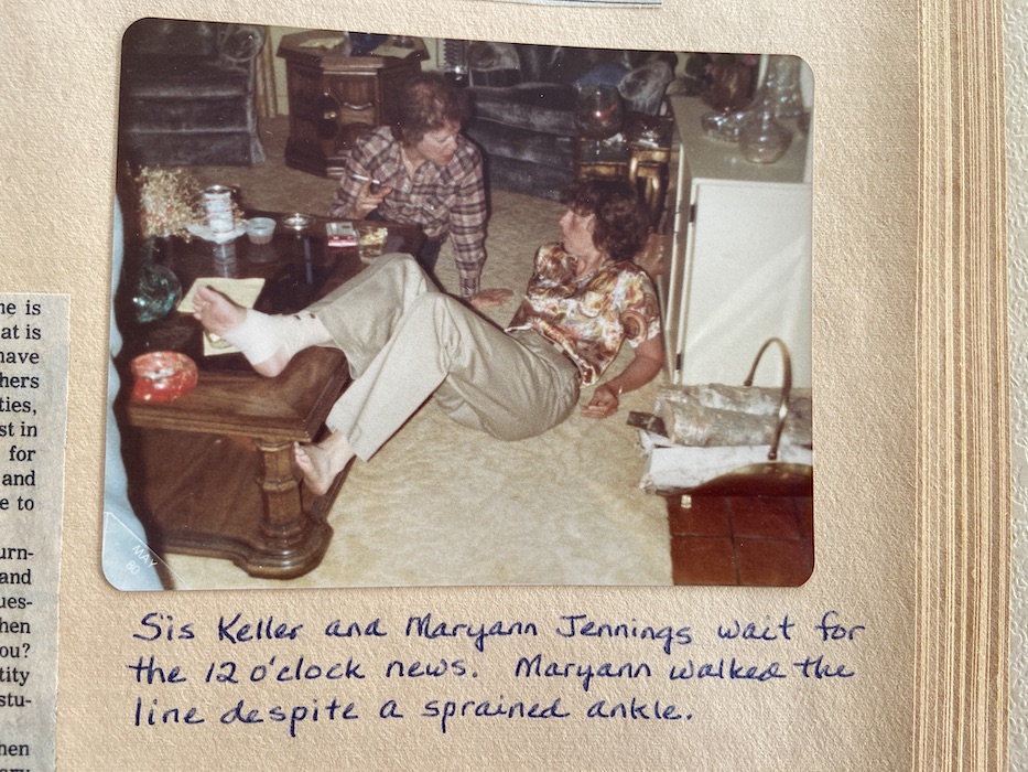 Sis Keller and Maryann Jennings sitting on the floor. Maryann has her sprained ankle propped up on a table.