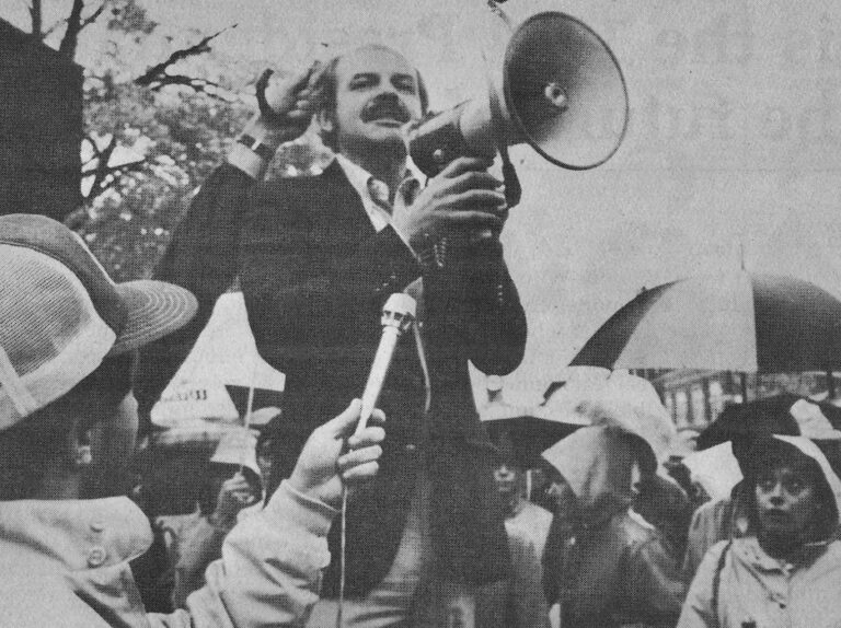 James Papachristos standing in front of a crowd with a bullhorn.