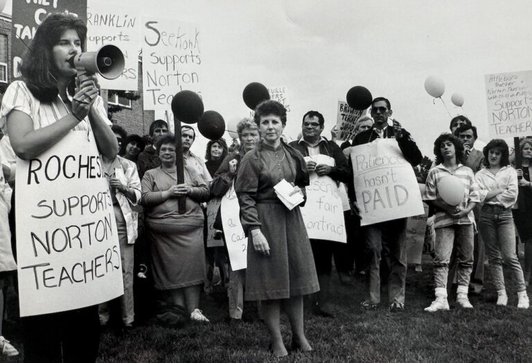 Diane Giordano stands alongside crowd of picketers.