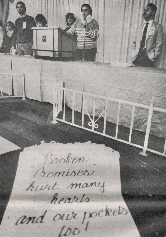 Sign with Richard Liston speaking at podium in the background.
