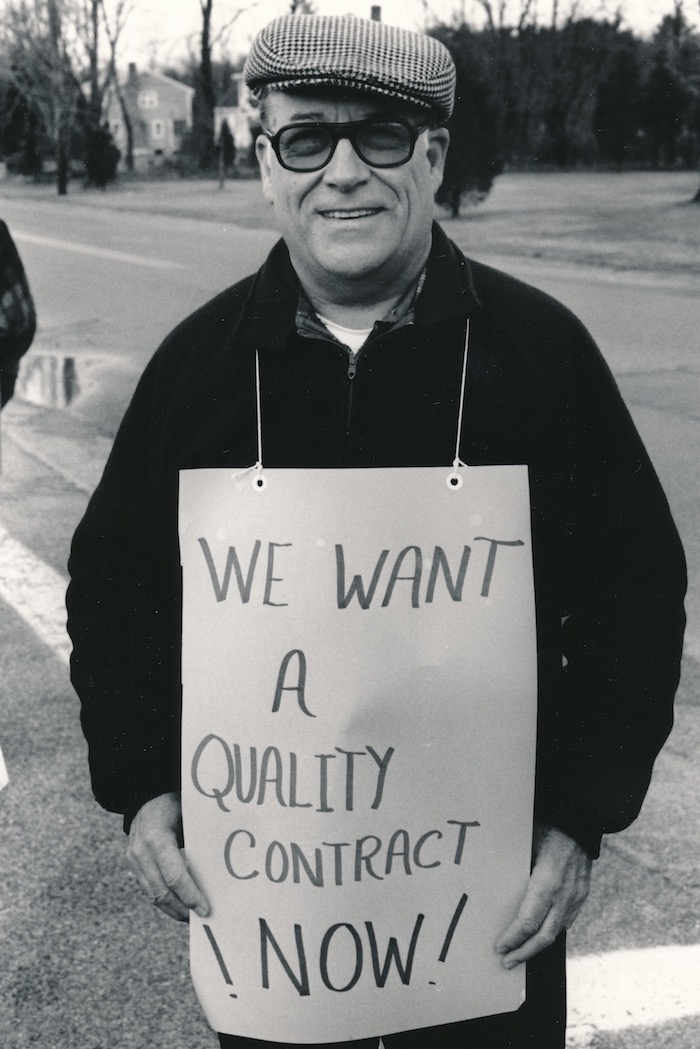 Picketer wearing a sign supporting the Raynham strike.