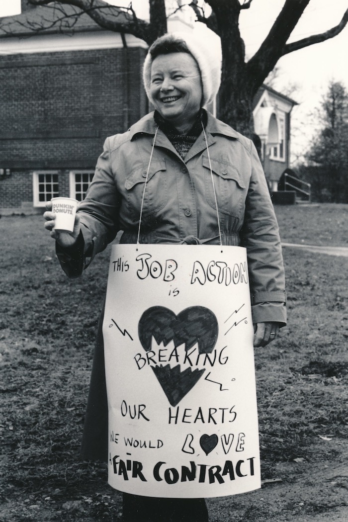 Picketer smiling and wearing a sign supporting the Raynham strike.