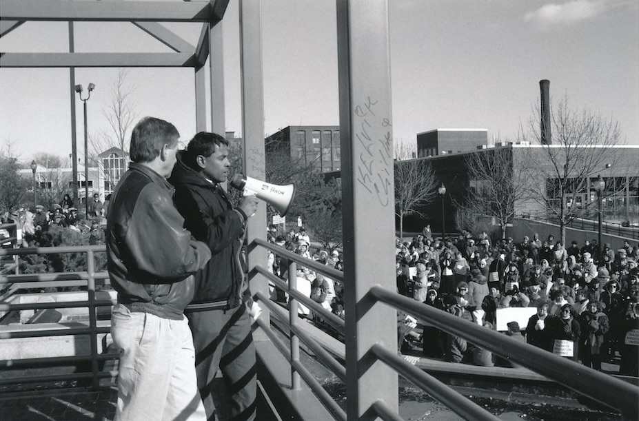 Two people in front of a crowd, one with bullhorn.