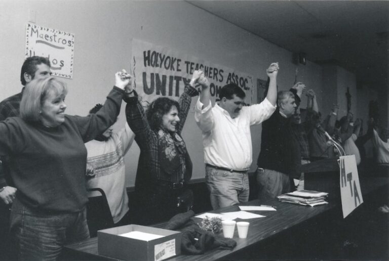Line of people holding hands with raised arms.