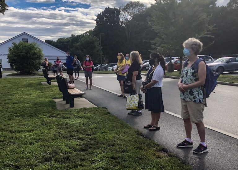 Andover educators stand far apart in a line on a sidewalk.