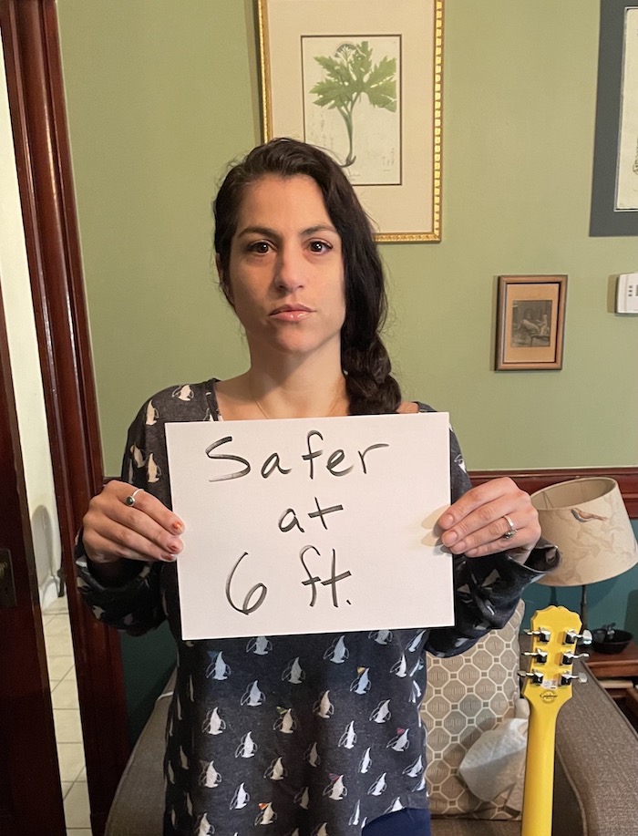 A Brookline teacher holding a sign supporting the strike while in her home.