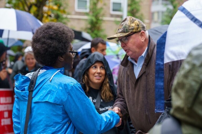 Steve Tolman shakes hands with someone in a crowd.