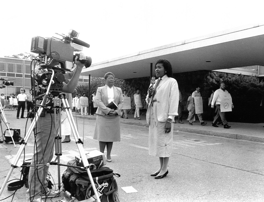 Camera man filming a reporter in front of picket line.