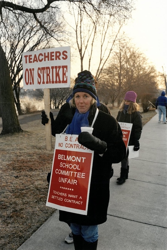 Two picketers with signs supporting the Belmont strike on a sidewalk.
