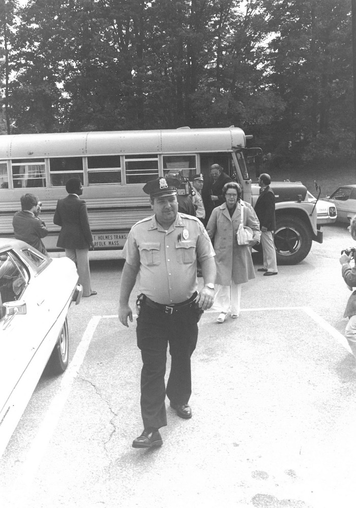 Police officer leading people off a school bus.
