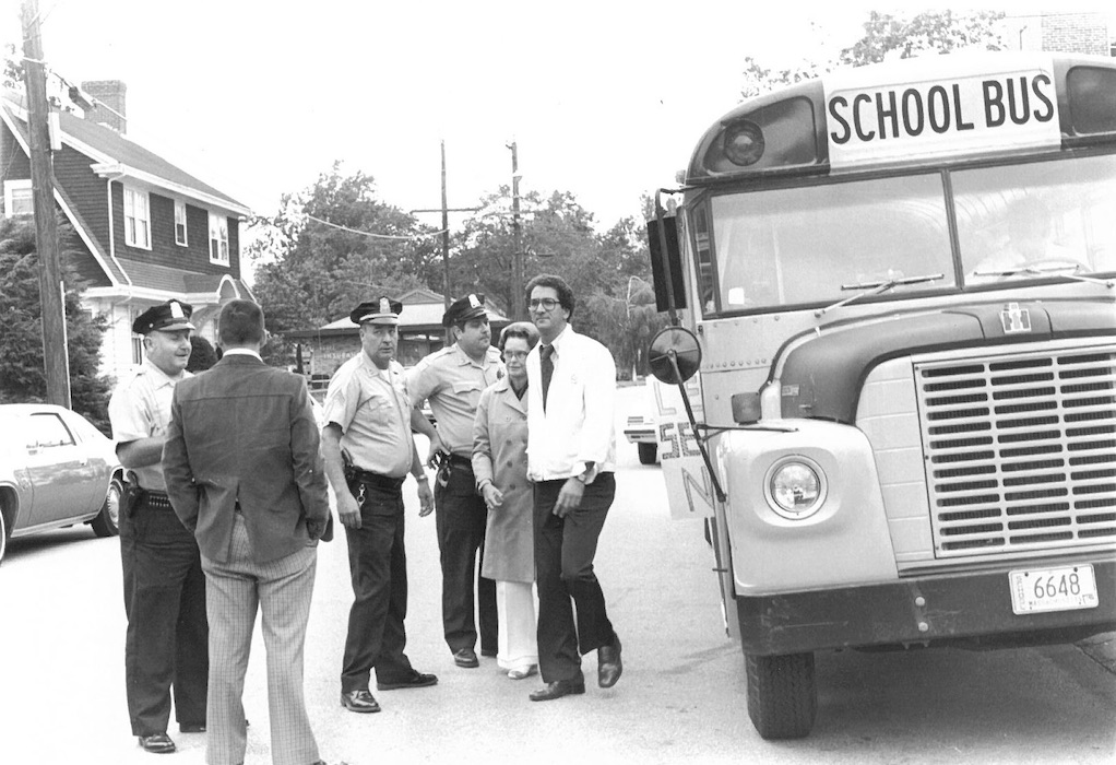 Group of police officers beside a school bus.