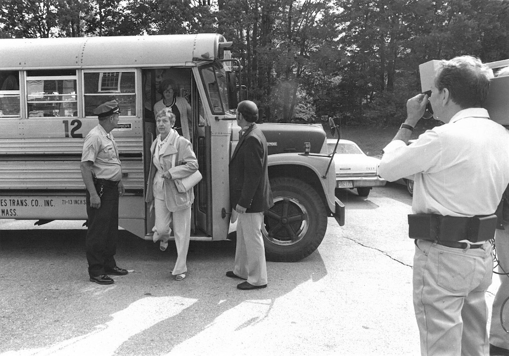 Camera man filming police officer letting people off of a school bus.