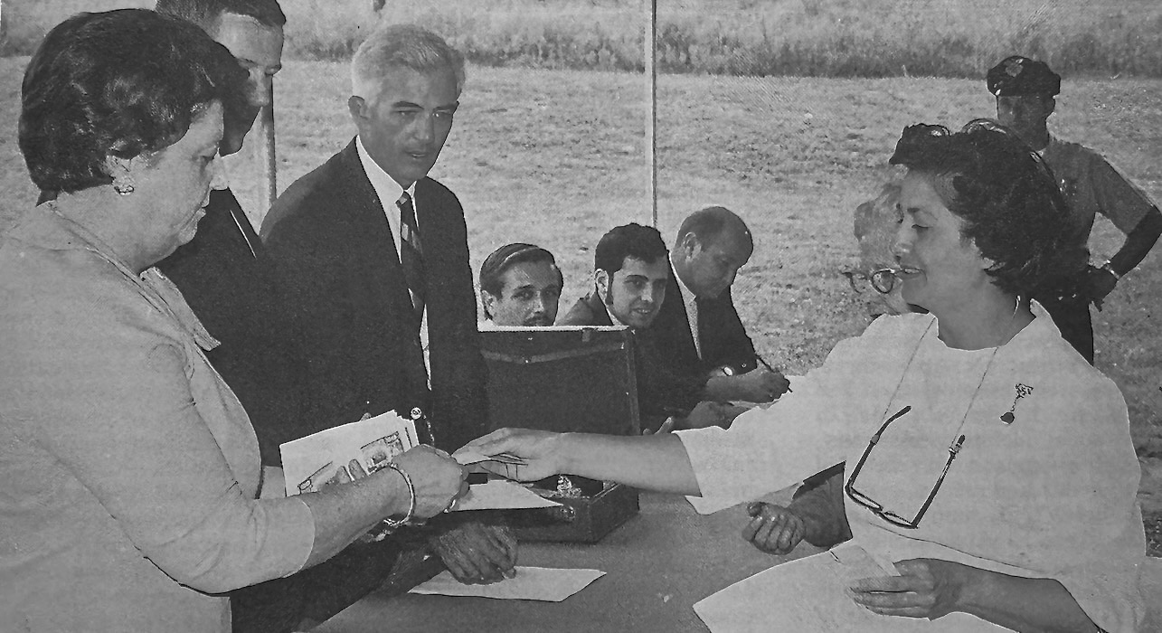 Helen O'Brien handing a paper to Mary Pinheiro.