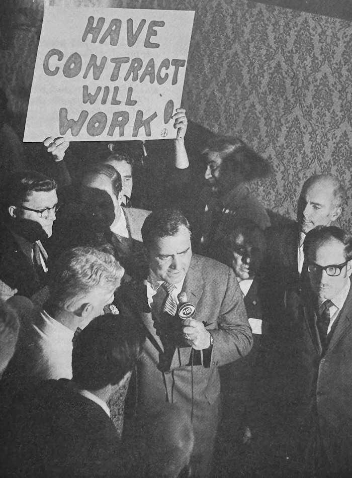 Frederick Lambert holds a microphone and addresses a crowd.