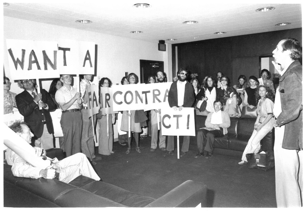 Group of picketers in a room holding signs supporting the New Bedford strike.