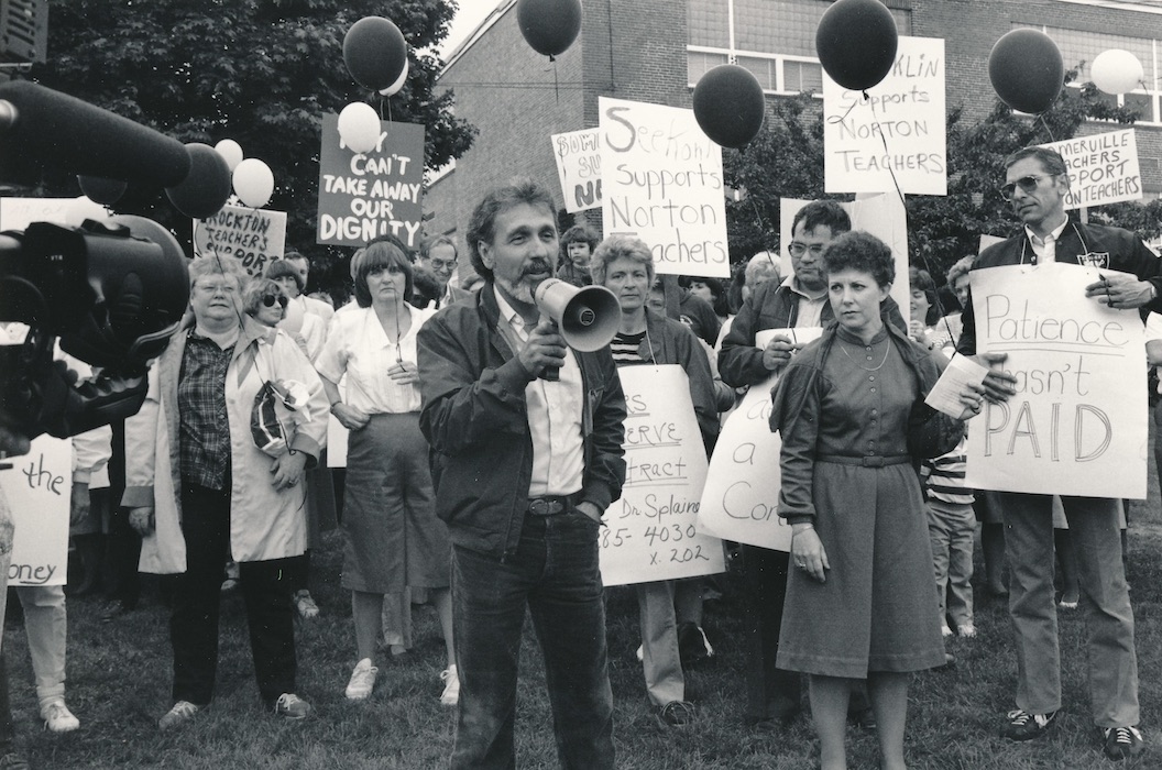 Man in front of a crowd of picketers with a bullhorn.