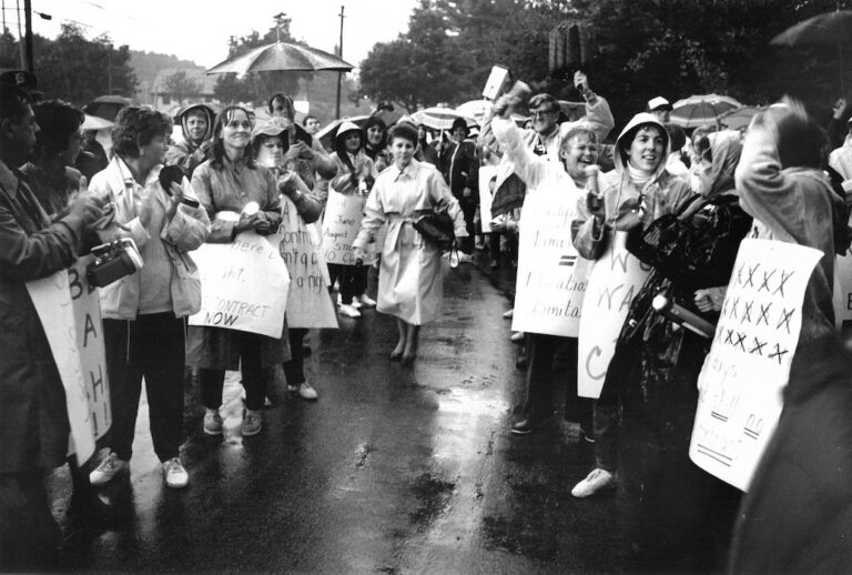 Diane Giordano walking through crowd of picketers in the rain.