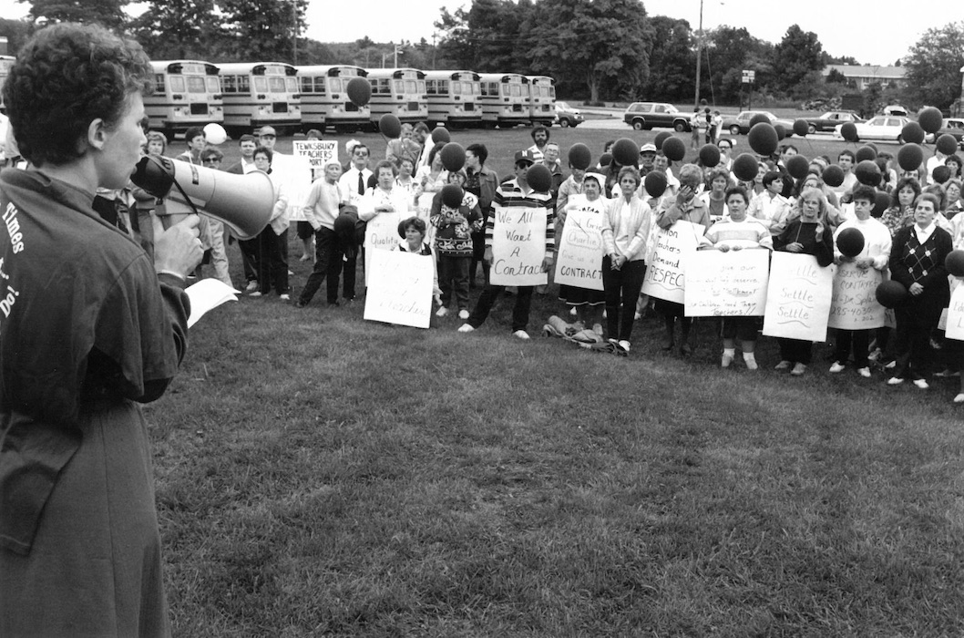 Woman in front of crowd of picketers with a bullhorn.