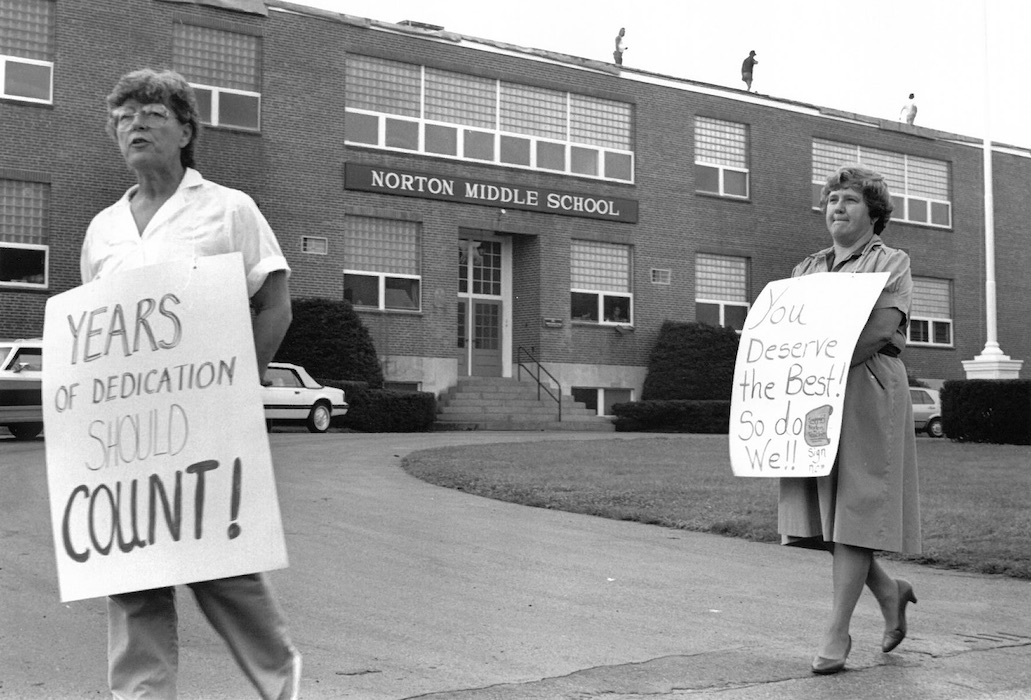 Two picketers with signs supporting the Norton strike in front of Norton Middle School.