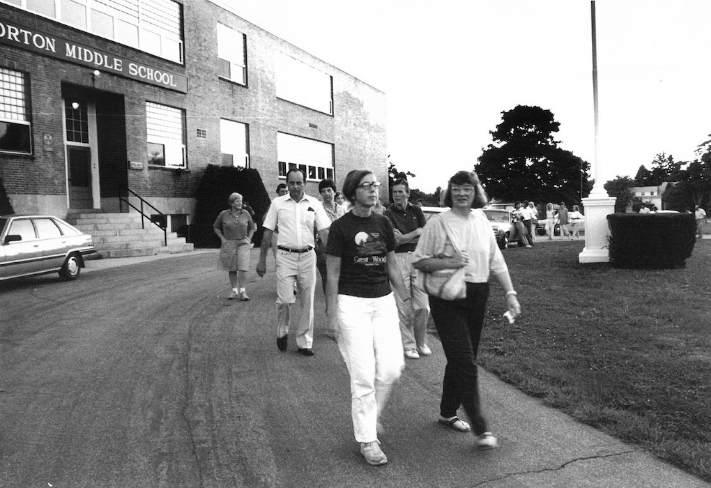 A line of people walking in front of Norton Middle School.