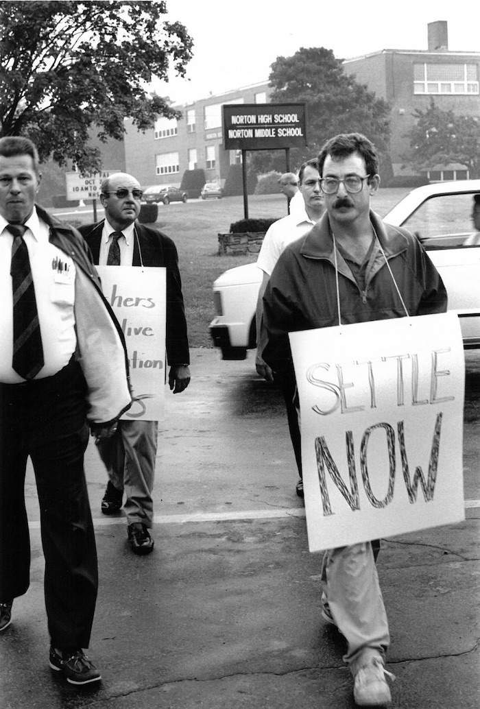 Picketers with signs supporting the Norton strike in front of a school.