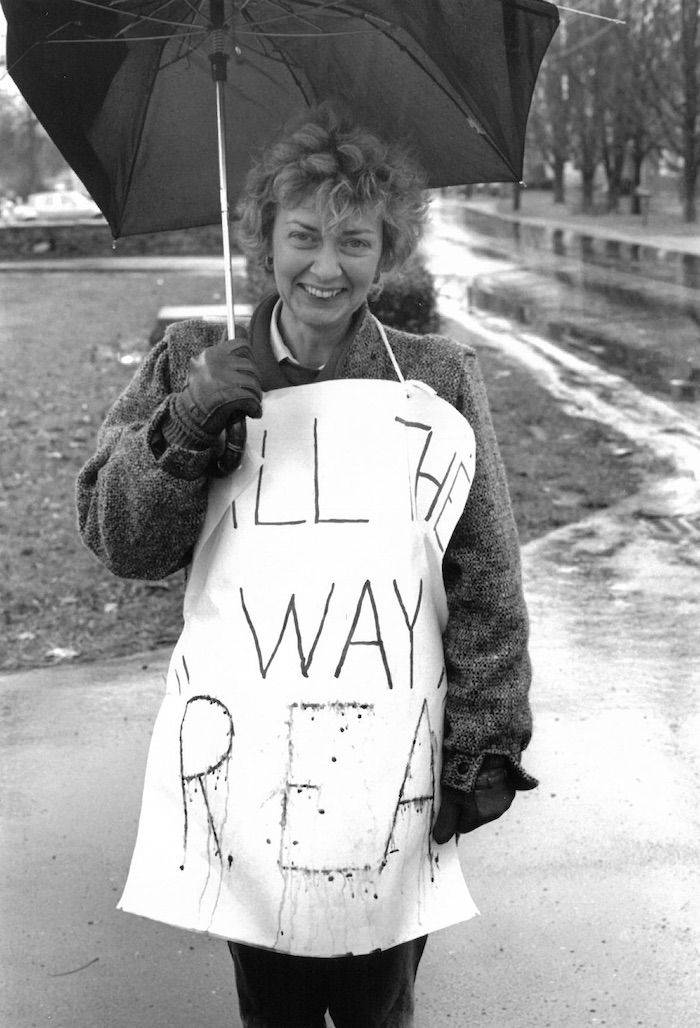 Picketer holding an umbrella and wearing a sign supporting the Raynham strike.