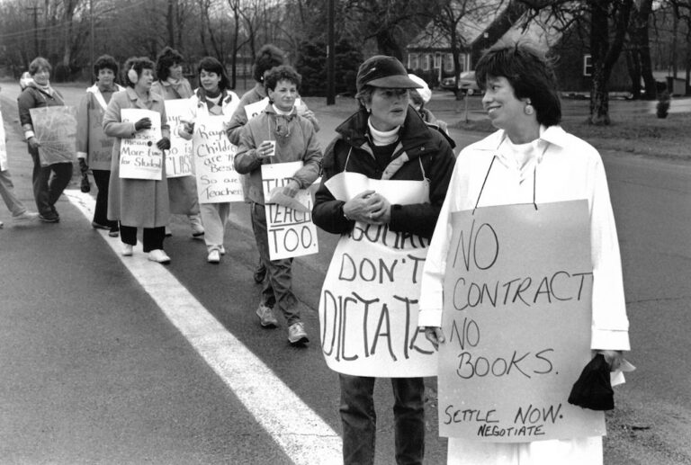 Line of picketers crossing a street with signs supporting the Raynham strike.