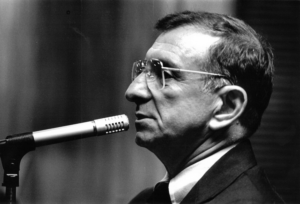 Side profile of a man in front of a microphone.