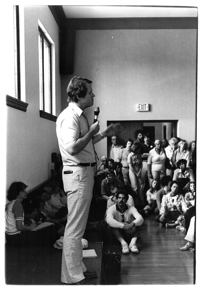 Man standing in front of a crowd holding a microphone.