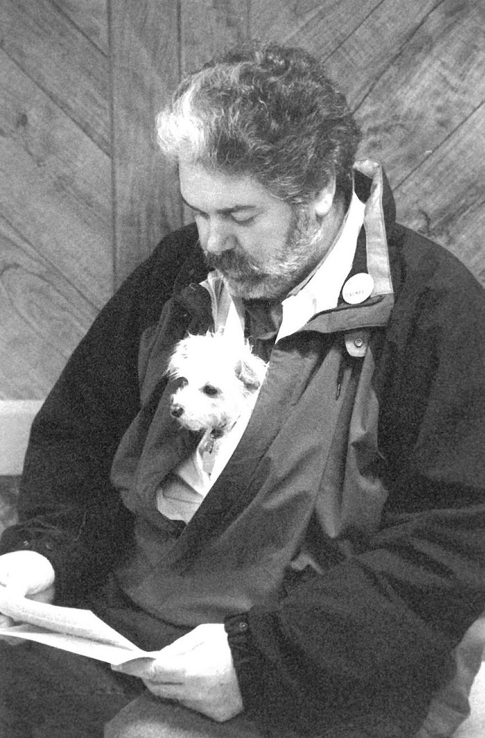 Person reading papers with a dog in their coat.