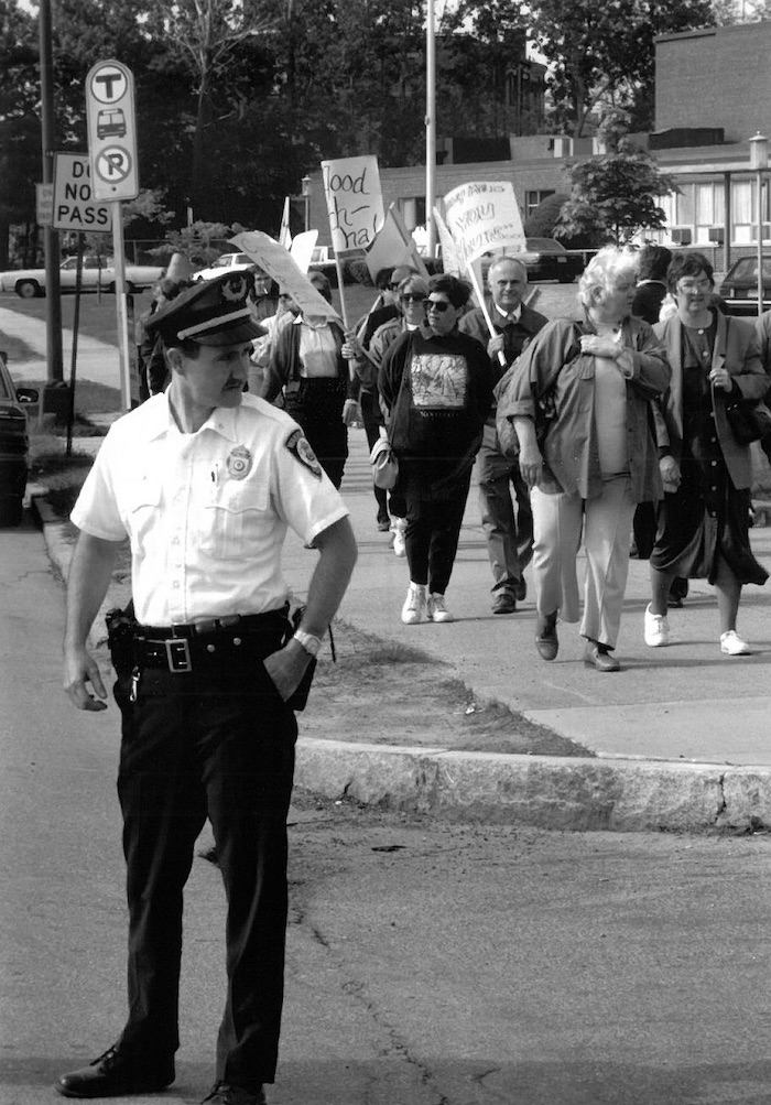 Police officer in front of crowded picket line.