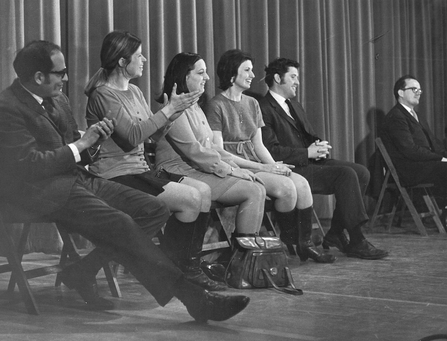 Line of people seated besides each other.